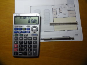 住宅ローンの返済額が計算できる電卓と住宅の間取りのプラン設計図面と三角スケールとステッドラーのシャープペンシル