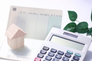 銀行の通帳と電卓と家の模型