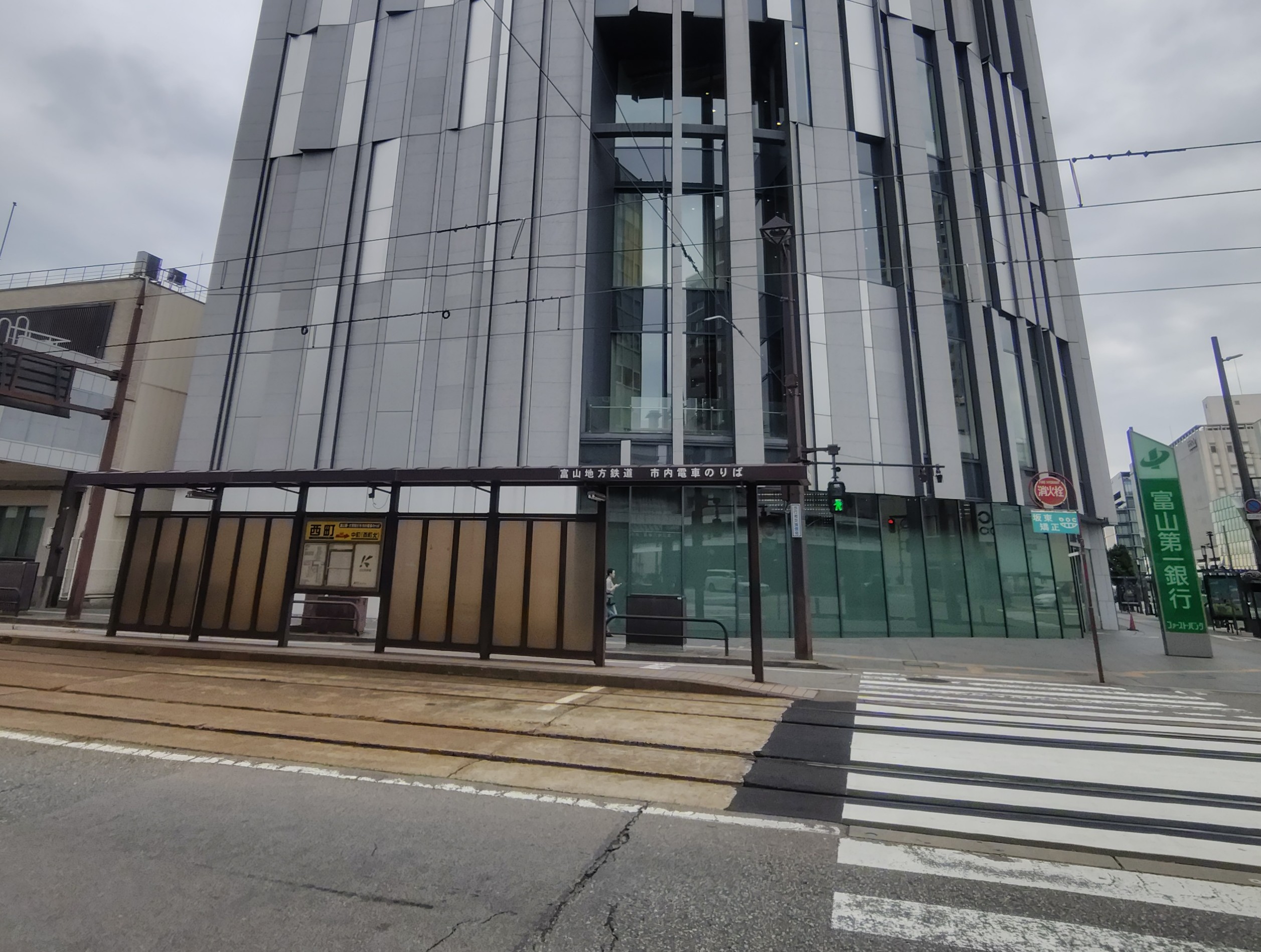 市電の停留所の背景に富山市ガラス美術館が映っている画像